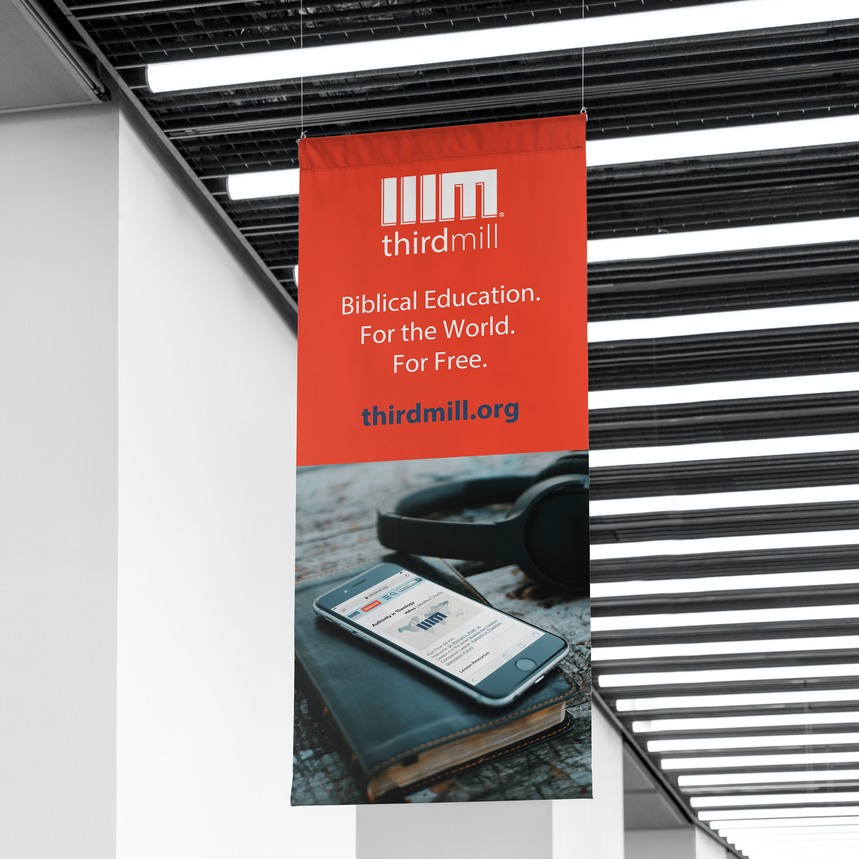 Red hanging banner promoting an event or organization inside a modern building.